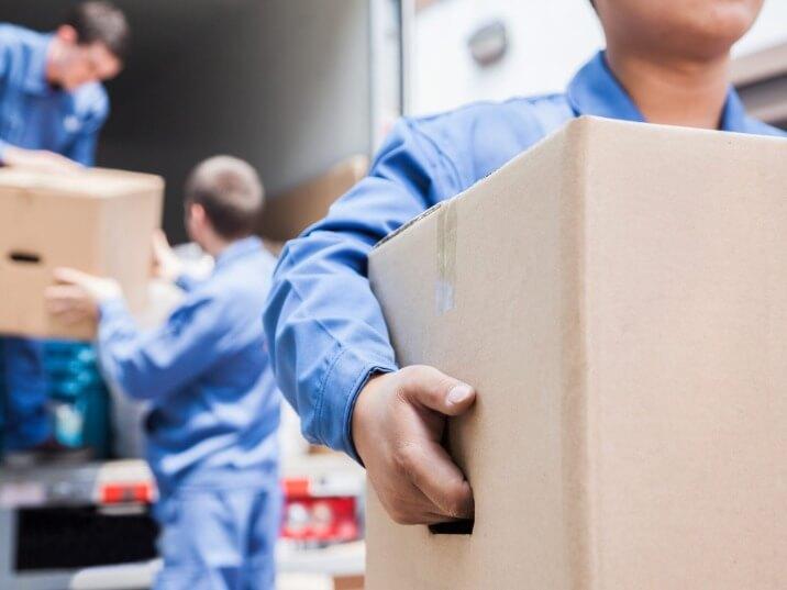 movers navigating a large sofa through a doorway